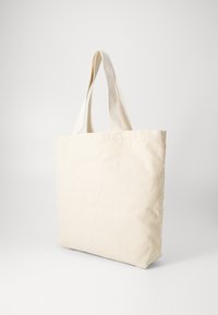 Μπεζ τσάντα χιαστί από κοτλέ με δύο υφασμάτινες λαβές, ορθογώνιο σχήμα και κατακόρυφη ραβδωτή υφή. Μινιμαλιστικός σχεδιασμός χωρίς ορατό λογότυπο.