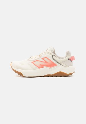 Beige athletic shoe with a textured upper, pink accents, and a light gum sole. Features a prominent 'N' logo and a cushioned, lightweight design.