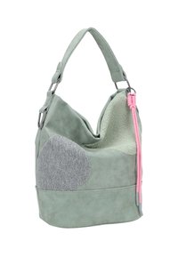 Zachte groene suède schoudertas met gestructureerde lichtgrijze en saliegroene patches en twee roze koordtassels aan de zijkant.