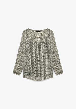 Blusa de manga larga en una tela ligera, con un patrón de rejilla en colores negro y cremita, con una ligera abertura en el escote y mangas fruncidas.