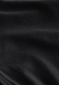 Tessuto nero liscio con sottili riflessi di luce e pieghe morbide che creano una texture delicata e profondità.