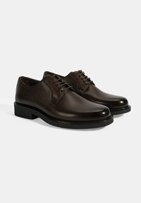 Bruine leren nette schoenen met een gladde afwerking, ronde neus en een klassiek vetersluiting ontwerp. Stevige zwarte rubberen zool met minimale profiel.