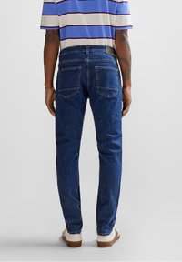 Herrblå denimjeans med fem fickor, rak bendesign, ljus tvätt och kontrasterande sömmar. Bärs med en randig t-shirt och vita sneakers.