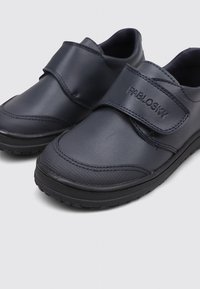 Une paire de chaussures noires en cuir pour enfants avec des bandes Velcro, de la marque "Pablosky," présentant des embouts texturés et des semelles en caoutchouc sur un fond clair.