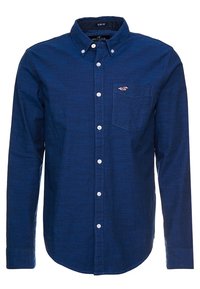 Pánská slim fit tmavě modrá košile na knoflíky s dlouhými rukávy, přední kapsou na hrudi a bílými knoflíky.