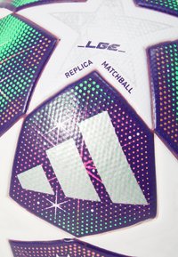 Soccer ball featuring a white surface with colorful, dotted accents in green, purple, and pink, displaying a prominent brand logo and text.