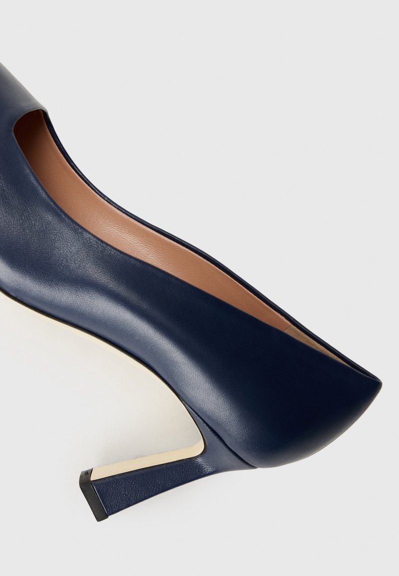 Scarpa con tacco alto in pelle blu navy, dal design elegante, con taglio aperto e tacco texturizzato con accenti dorati. Rivestimento interno liscio in beige.