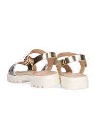 Sandalias metálicas doradas con hebilla ajustable, espalda descubierta, suela ancha de plataforma blanca y rayas multicolores en los lados.