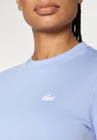 Ανοιχτό μπλε βαμβακερό t-shirt με στρογγυλή λαιμόκοψη, που διαθέτει μικρό λευκό κεντημένο λογότυπο στην αριστερή πλευρά του στήθους.