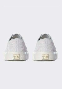 Sneaker in suede grigio con suola in gomma bianca, caratterizzati da un retro testurizzato e un'etichetta logata dorata sul tallone.