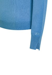 Maglione a maglia di colore azzurro chiaro con polsini e orlo a coste, fessure laterali e un dettaglio decorativo con logo sulla manica. Tessuto morbido, vestibilità rilassata.
