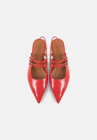 Red patent leather pointed-toe slingback shoes with two strap accents. Smooth texture and a sleek design highlight the footwear's contemporary style.