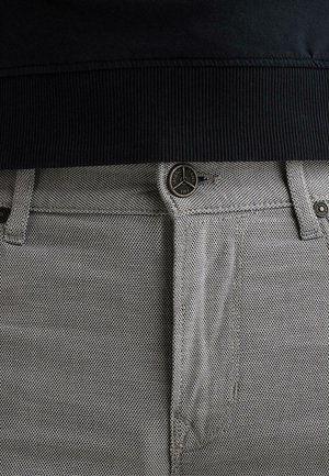 Primer plano de vaqueros grises con textura, con un botón metálico etiquetado "Legend Jeans PME" y una cintura negra acanalada encima.