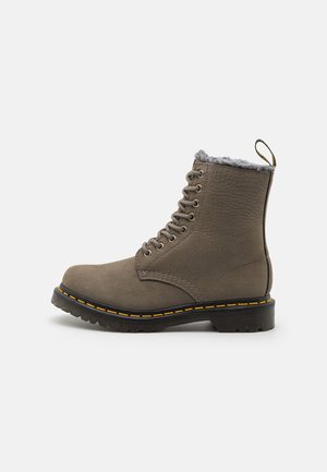 Brown leather lace-up ankle boot with a textured finish, grey faux fur lining, yellow stitching accents, and a sturdy rubber sole.