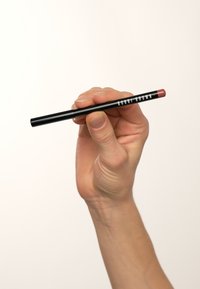 Crayon à lèvres noir tenu dans une main, avec une pointe rosée et un texte blanc indiquant "BOBBI BROWN" sur le côté.