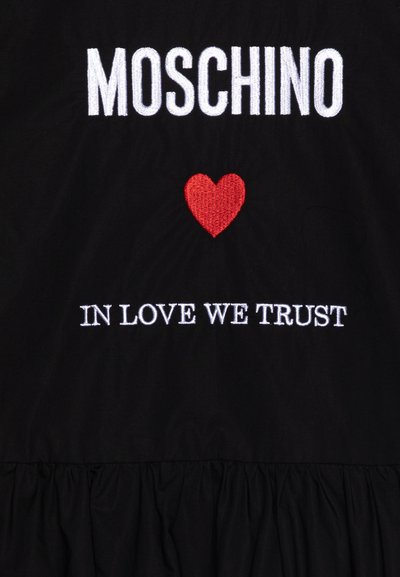 Tessuto nero con testo ricamato bianco "MOSCHINO" e "IN LOVE WE TRUST," con un dettaglio a forma di cuore rosso. Orlo arricciato nella parte inferiore.