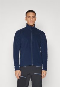 Navy blue fleece jacket with a high collar, full front zipper, and two side zip pockets; soft texture with a close-fitting design.