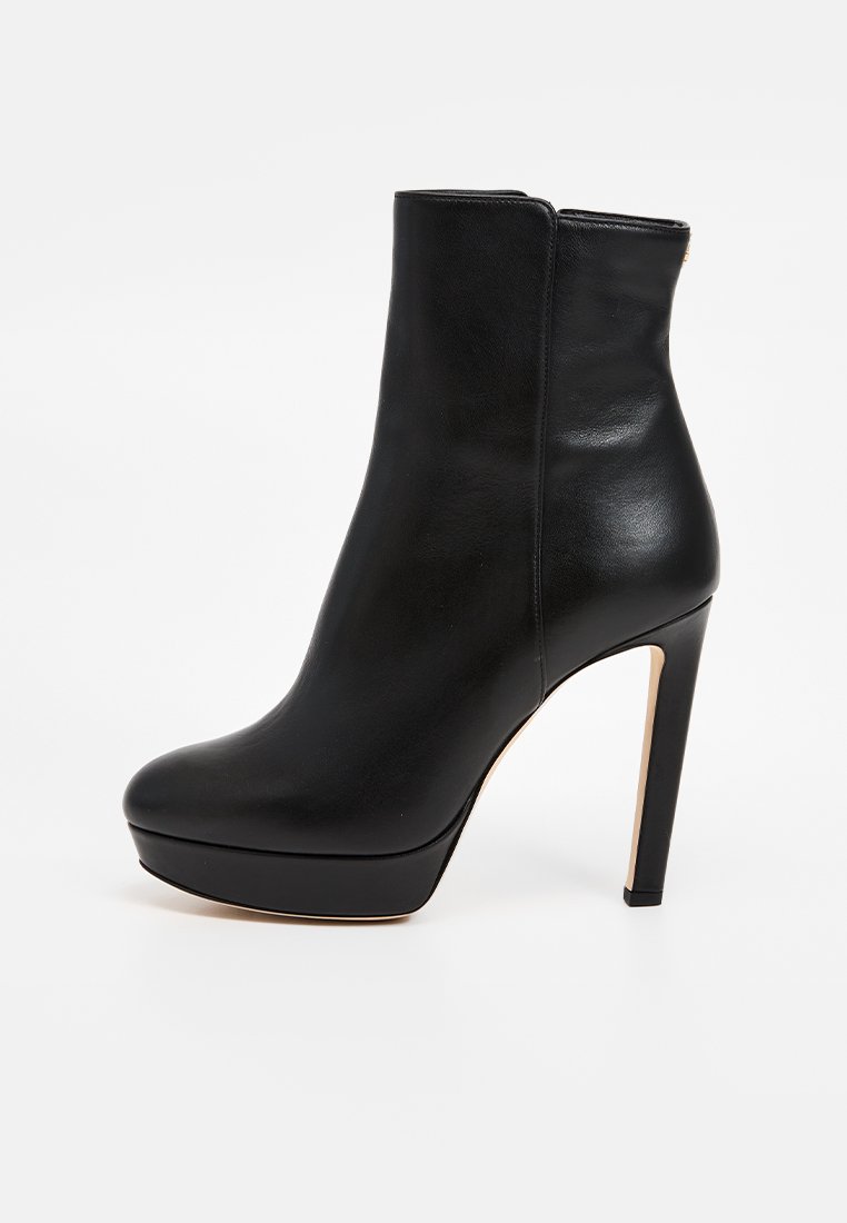 Bottine en cuir noir avec un design sleek et ajusté, talon aiguille haut et bout arrondi. Texture lisse avec un minimum de matériel.