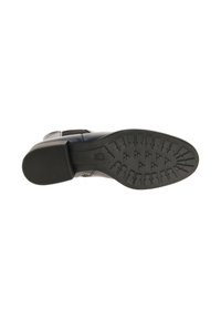 Zwarte rubberen zool met een getextureerd grippatroon; leren bovenwerk met contrasterende designelementen; platte hak voor stabiliteit.