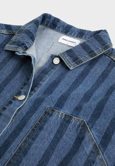 Veste en denim avec des rayures verticales foncées, fermeture par boutons, poche poitrine et une étiquette "BOBO CHOSES" visible à l'intérieur du col.