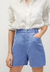 Spodenki dżinsowe w kolorze niebieskim z wysokim stanem, z przednimi kieszeniami, zapięciem na guzik oraz widocznymi detalami przeszyciami. Materiał wydaje się solidny i gładki.