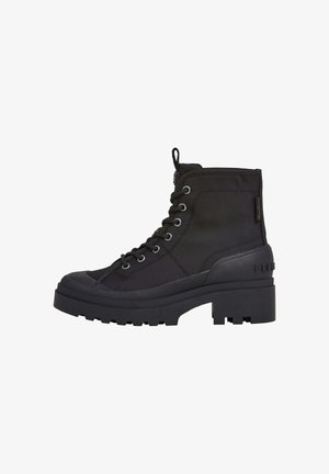Botas negras de tobillo hechas de un tejido duradero, con cordones en la parte delantera, punta redonda, suela de goma gruesa y detalles texturizados en los costados.