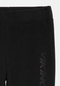 Schwarze Fleece-Hosen mit glatter Textur, elastischem Taillenbund, seitlichem Schlitz und einer Markenakzentuierung entlang des Beins.