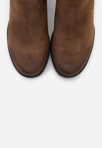 Braune Leder-Stiefeletten mit glatter Textur, abgerundetem Toe und schwarzer Gummisohle. Keine sichtbaren Muster oder Verzierungen.