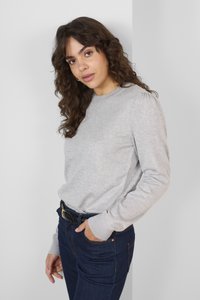 Maglione grigio chiaro a maglia con maniche lunghe e collo rotondo. Abbinato a jeans blu scuro e a una cintura nera con fibbia dorata.