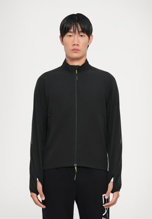 Black athletic jacket with a high collar, full front zipper, and long sleeves. Features reflective accents and a slim fit design.