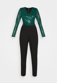 Top en sequins verts à manches longues et décolleté en V profond, associé à un pantalon noir fuselé. Dispose d'une fermeture éclair au dos.