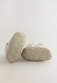 Chaussures beiges avec une tige en tissu texturé et des semelles en caoutchouc à motifs ornées d'arcs-en-ciel en relief. Bandes Velcro pour une mise en chaussure facile.