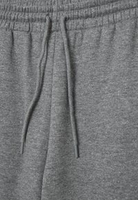 Graue Sweatpants mit strukturiertem Finish, ausgestattet mit einem elastischen Taillenbund und Kordelzug. Subtile Funken von Glitzer im gesamten Stoff.