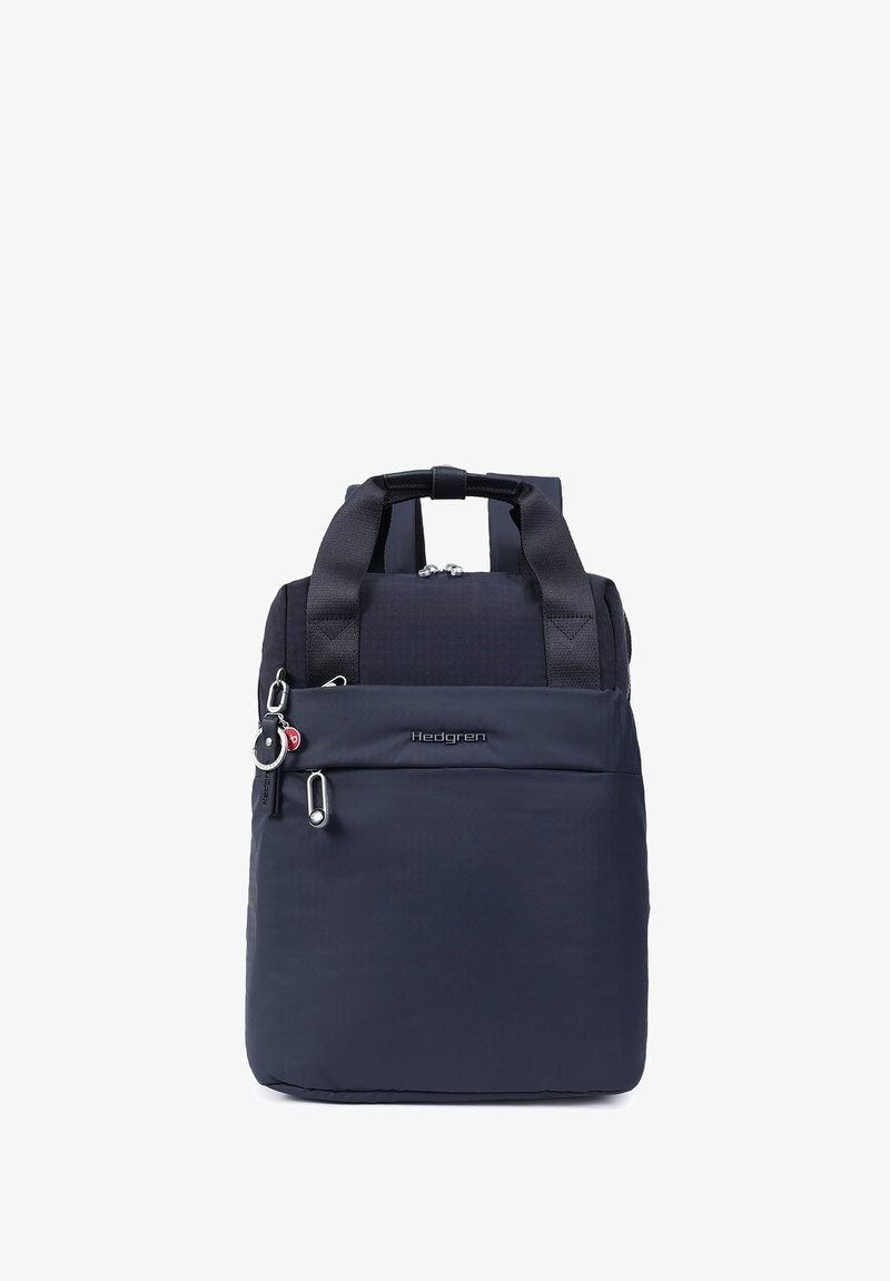 Petit sac à dos Hedgren bleu marine avec deux poignées supérieures, une poche avant zippée et un porte-clés rond attaché au curseur de la fermeture éclair.