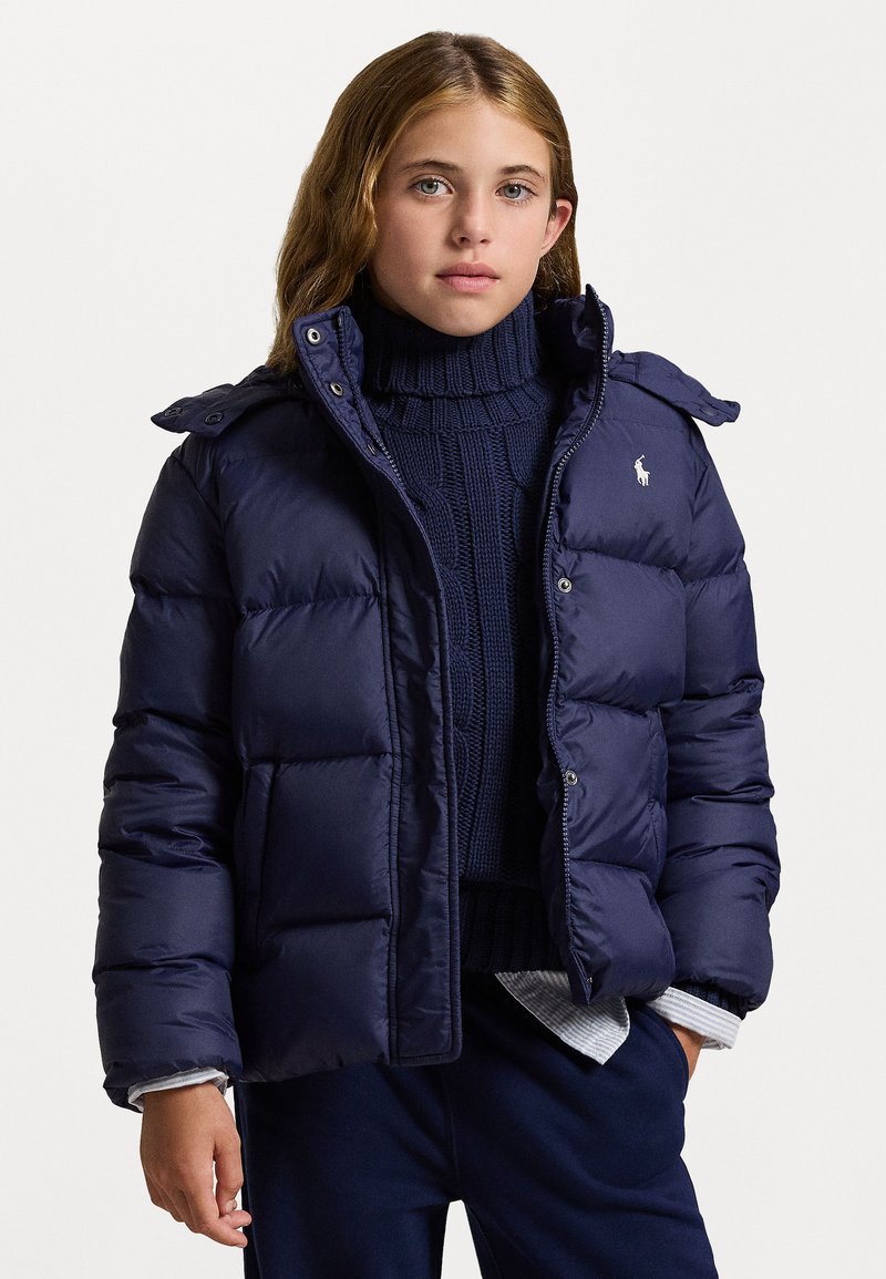 Navy puffer jacket with a high collar, snap-button closure, and side pockets. Features rugged stitching and a logo on the chest.
