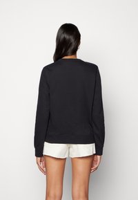 Czarna bluzka z bawełny z okrągłym dekoltem, ściągaczami przy mankietach i u dołu, o gładkiej strukturze i luźnym kroju.