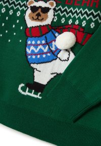 Grüner gestrickter Pullover mit einem Bären in Sonnenbrille, der einen bunten Schal und einen Pullover trägt, mit einem Pompon-Detail und auf Eis läuft.