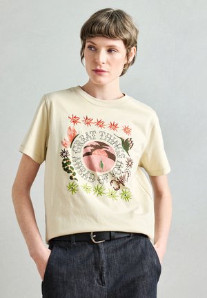 T-shirt di cotone color crema con grafica centrale raffigurante piante colorate e la scritta "GRANDI COSE TI ASPETTANO". Maniche corte.