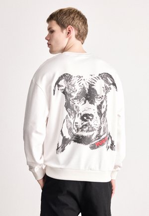 Weißes Sweatshirt mit einem schwarzen Skizzenmotiv eines Hundes auf der Rückseite, versehen mit rotem "HUGO"-Text. Rippbündchen und Saum, lockere Passform.