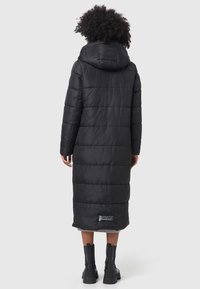 Long black puffer coat with a hood, quilted design, and side slits. Features a logo patch on the lower left and is made of shiny, smooth material.