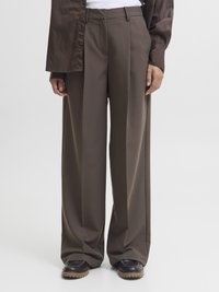 Calças largas castanhas com uma textura de tecido suave, apresentando uma cintura ajustada, pregas e um design limpo e bem cortado. Combinadas com sapatos escuros.