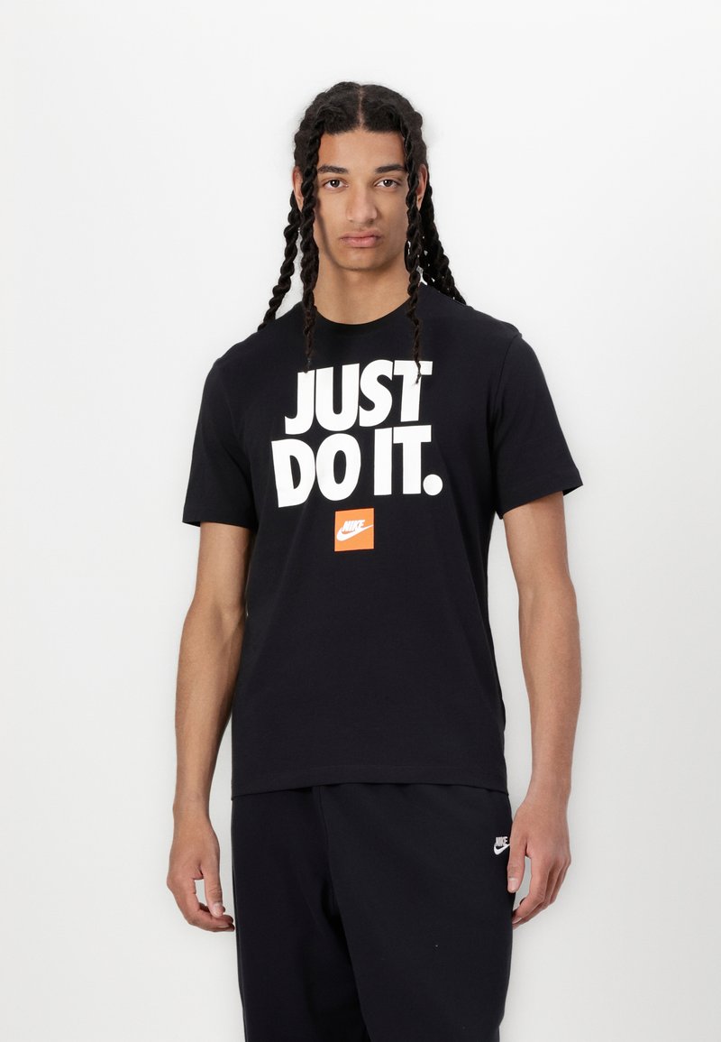 Juodas medvilninis marškinėliai su raiškia balta užrašu "TIK DARYK TAI." ir mažuoju oranžiniu Nike logotipu. Apvalios iškirptės ir trumpomis rankovėmis.