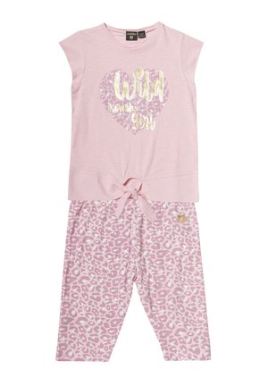Roze pyjama set met een T-shirt met korte mouwen, voorzien van een goudkleurige "Wild" grafiek binnen een hart, en een broek met luipaardprint en strikdetail.
