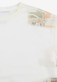 Biała koszulka z krótkim rękawem z teksturowanym nadrukiem w odcieniach pomarańczowego i szarego oraz wzorzystym żółtym akcentem przy dekolcie.