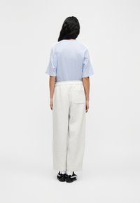 Ανοιχτό μπλε κοντομάνικο τοπ με λευκές λεπτομέρειες, σε συνδυασμό με γκρι φαρδιά αθλητικά παντελόνια. Το ντύσιμο ολοκληρώνεται με άνετα casual παπούτσια.