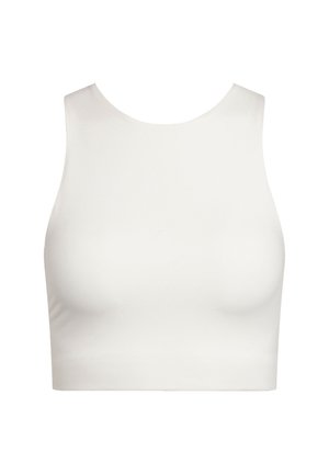 Smiling person with brown hair tied back, wearing a white sleeveless crop top and high-waisted black leggings, standing against a plain background.