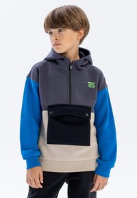 Sweatshirt à capuche avec un mélange de couleurs grises, bleues et beiges. Comprend une poche frontale avec fermeture à pression et des poignets côtelés.