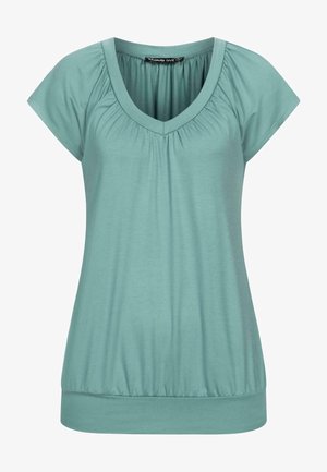 V-päinen, lyhythihainen toppi pehmeästä teal-kankaasta. Sisältää rypistetyn kaula-aukon ja istuvan helman, jossa on hieman joustoa mukavuutta varten.