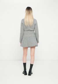 Rochie tricotată gri cu mâneci lungi, talie strânsă și fustă evazată. Confecționată dintr-un material moale, având o textură netedă și un design minimalist.