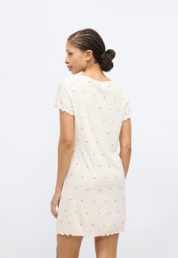 Νυχτικό με κοντά μανίκια σε ανοιχτό κρεμ χρώμα με ροζ σχέδια καρδιάς, ριμπ ύφανση, σκουληκότρυπα στο τελείωμα και άνετη γραμμή.